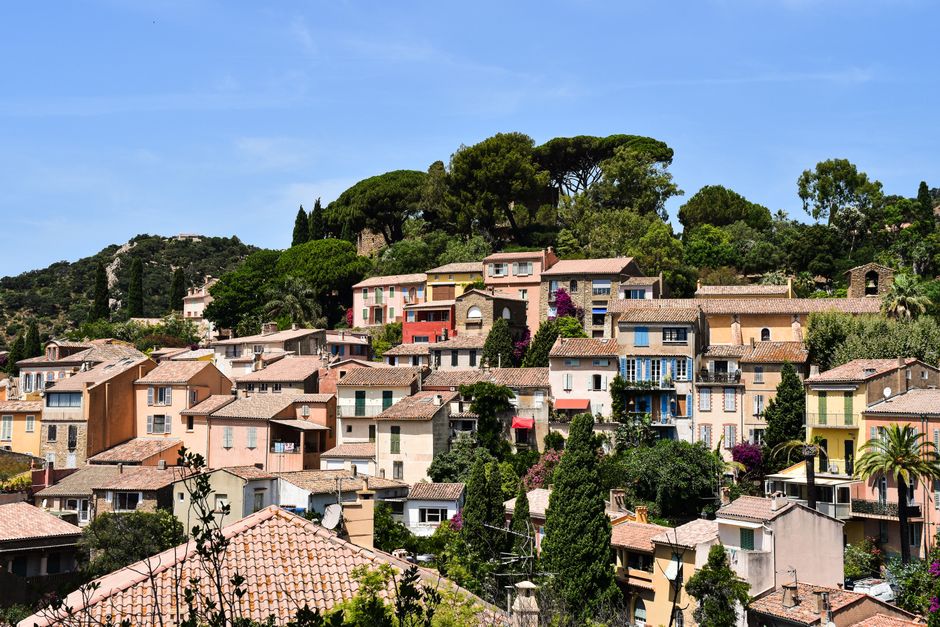 Vue pittoresque de maisons colorées à Bormes-les-Mimosas, Provence, France sous un ciel bleu clair.