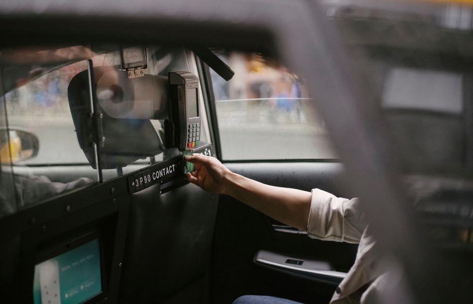 Un passager finalise une transaction de course de taxi en utilisant une carte de crédit sur un terminal de paiement dans le véhicule.