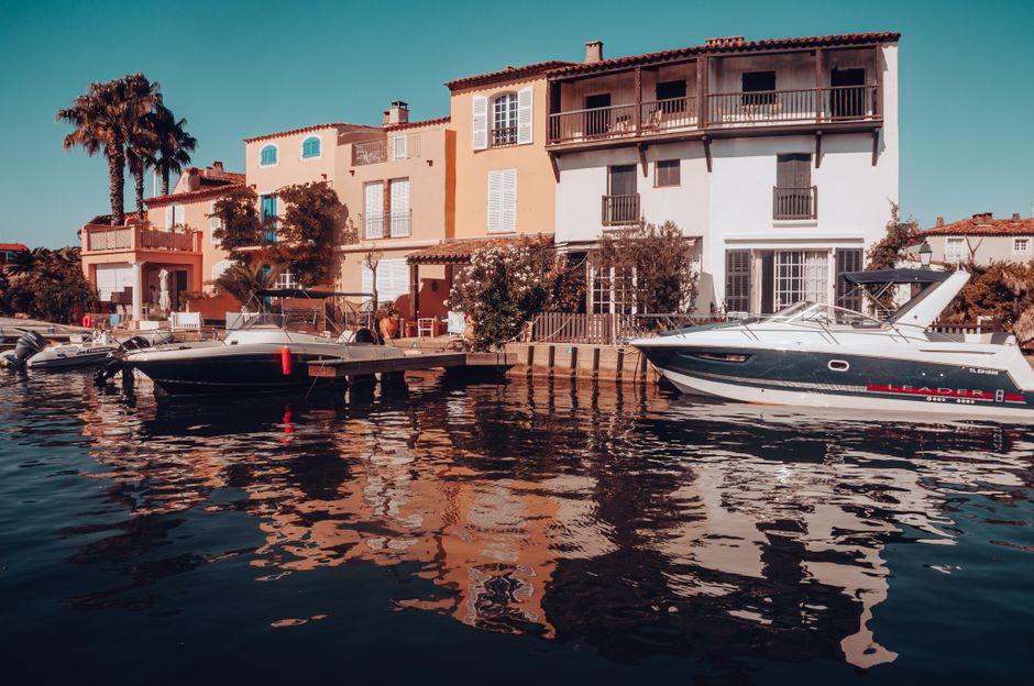 Vue pittoresque du front de mer à Grimaud, France, avec des bateaux amarrés et des villas colorées.