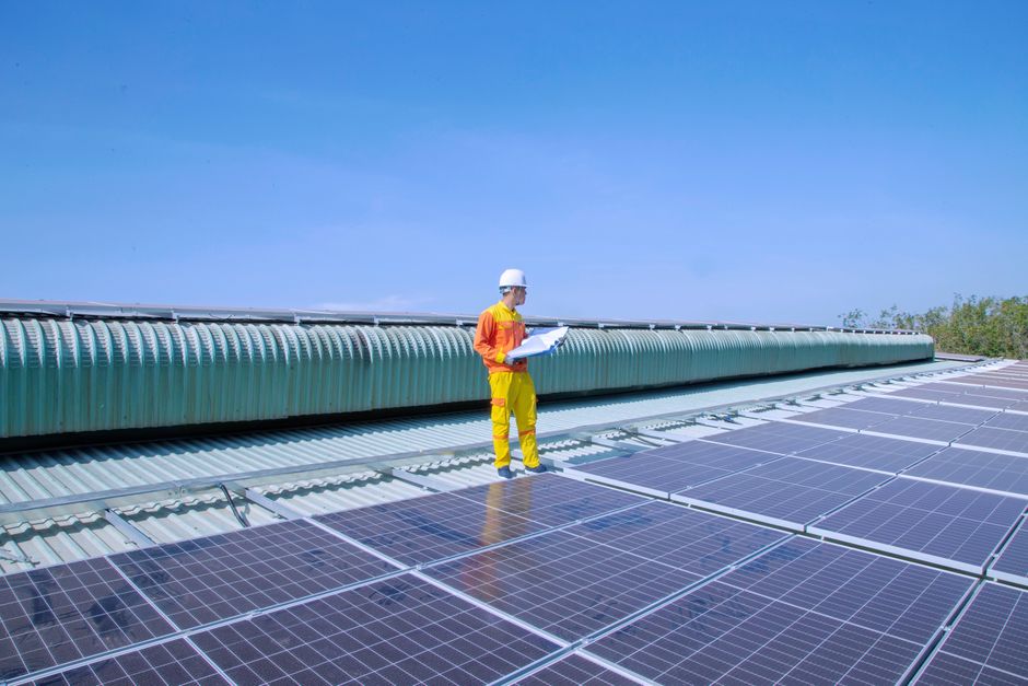 Technicien examinant des panneaux solaires sur un toit, mettant en avant l'énergie renouvelable.