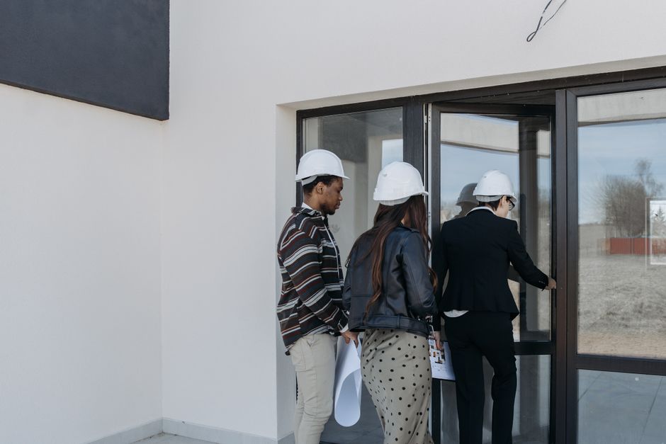 Un groupe de clients divers avec un agent immobilier à l'entrée d'un site de construction neuve.